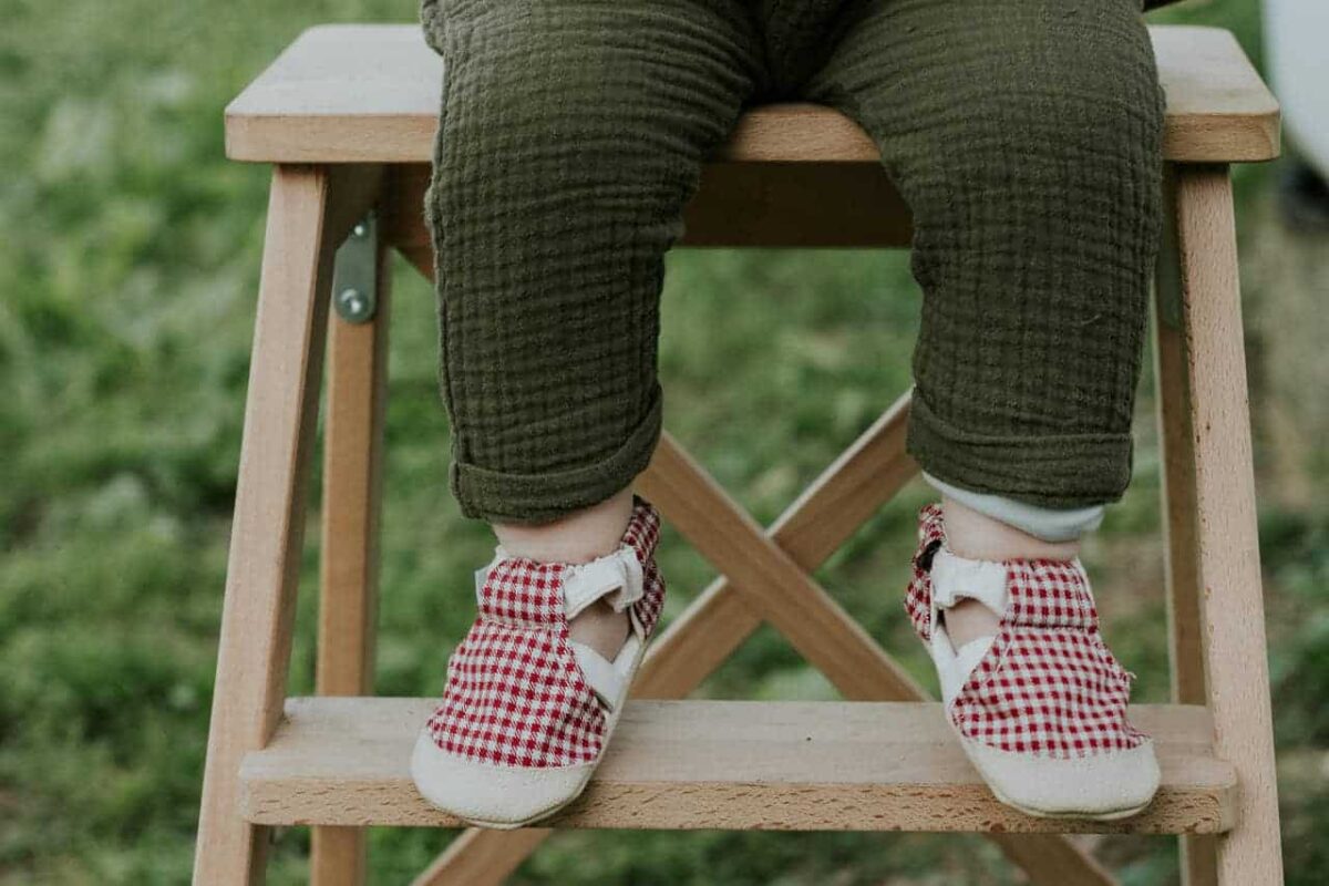a child's legs and feet on a wooden step stool